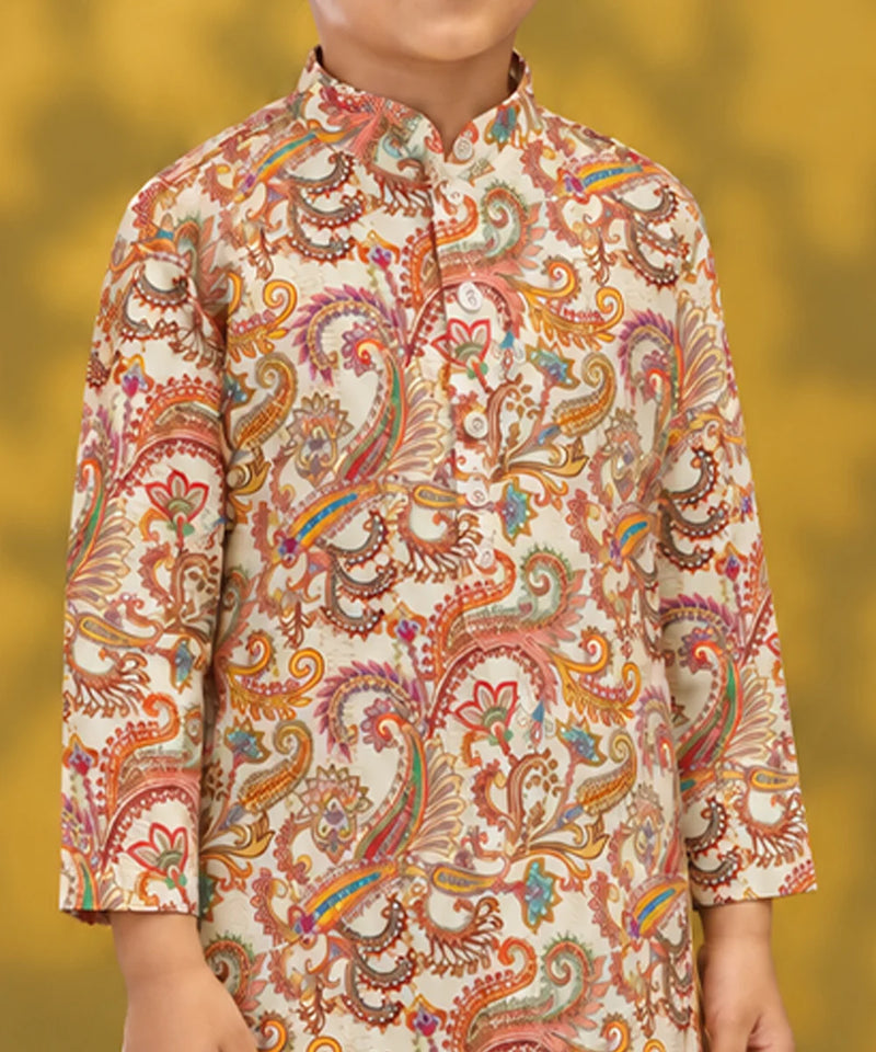A child wearing a cream-colored kurta with an intricate multicolor paisley pattern in orange, pink, yellow, and green, set against a soft yellow background.