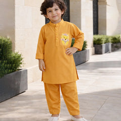 Child wearing a mustard yellow traditional outfit with a cartoon character, standing outdoors.