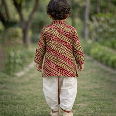 Child wearing a patterned kurta and white pants walking outdoors.