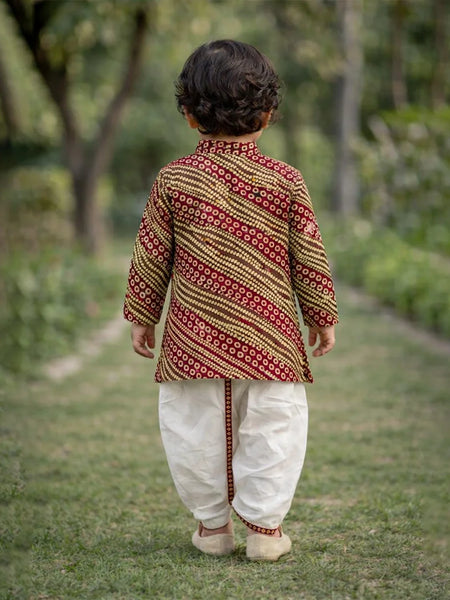Child wearing a patterned kurta and white pants walking outdoors.