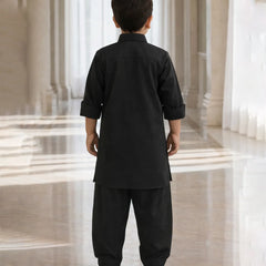 Child wearing a black traditional outfit standing in a marble hallway.