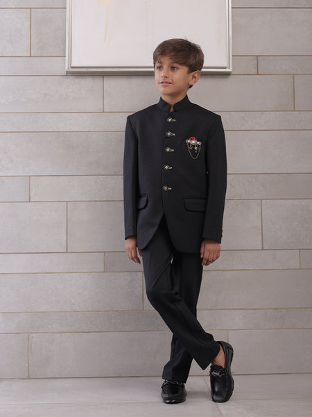  It is a black Jodhpuri suit set which consists of a Jodhpuri Coat along with matching pants. It features stylised buttons, a red coloured pocket square and a nice broach.
