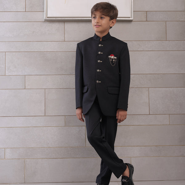  It is a black Jodhpuri suit set which consists of a Jodhpuri Coat along with matching pants. It features stylised buttons, a red coloured pocket square and a nice broach.