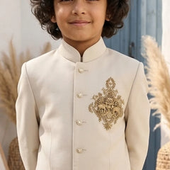 Child wearing a cream-colored embroidered traditional outfit with a blurred natural background