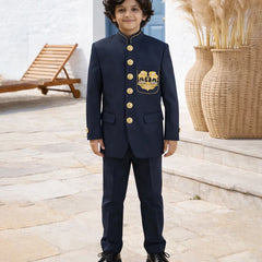 Young boy in a navy suit with gold buttons standing outdoors.