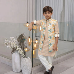 Young boy in traditional outfit standing indoors with decorative elements.