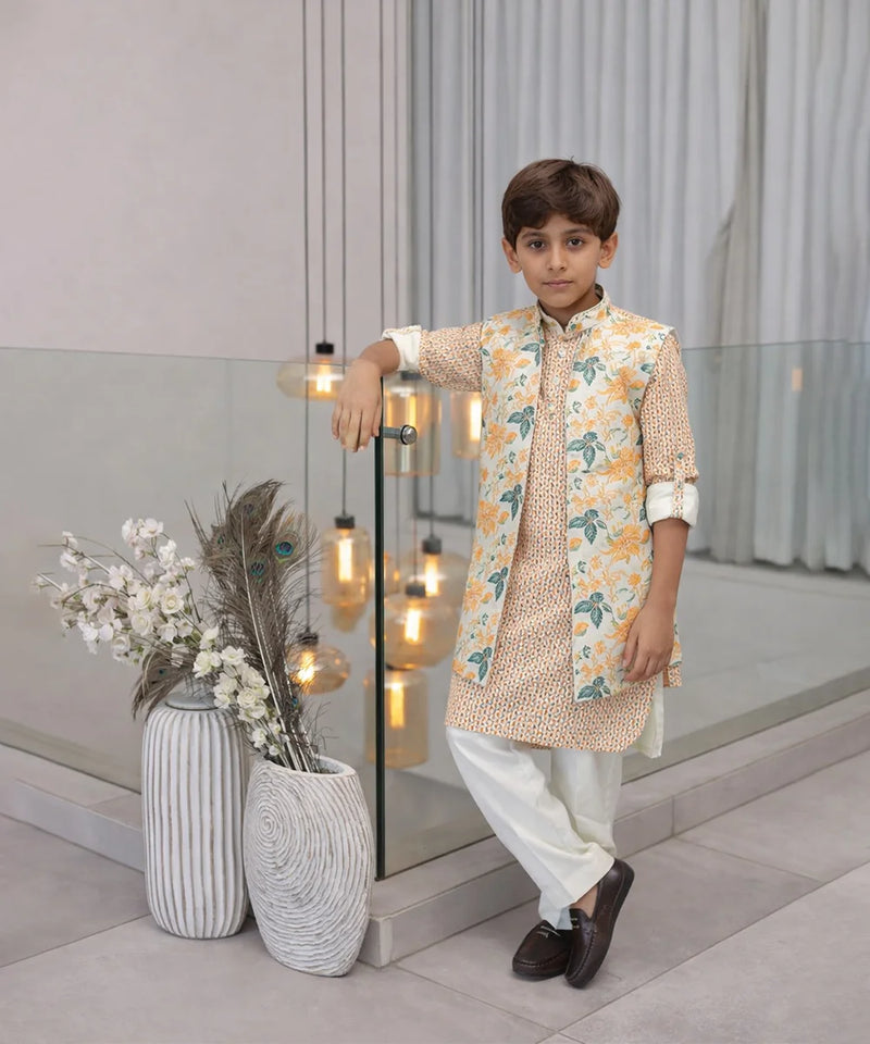 Young boy in traditional outfit standing indoors with decorative elements.