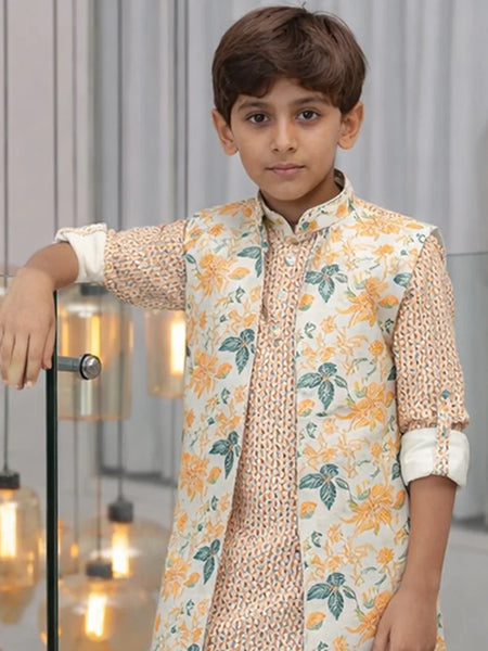 Young boy wearing a floral outfit in an indoor setting with decorative lights.