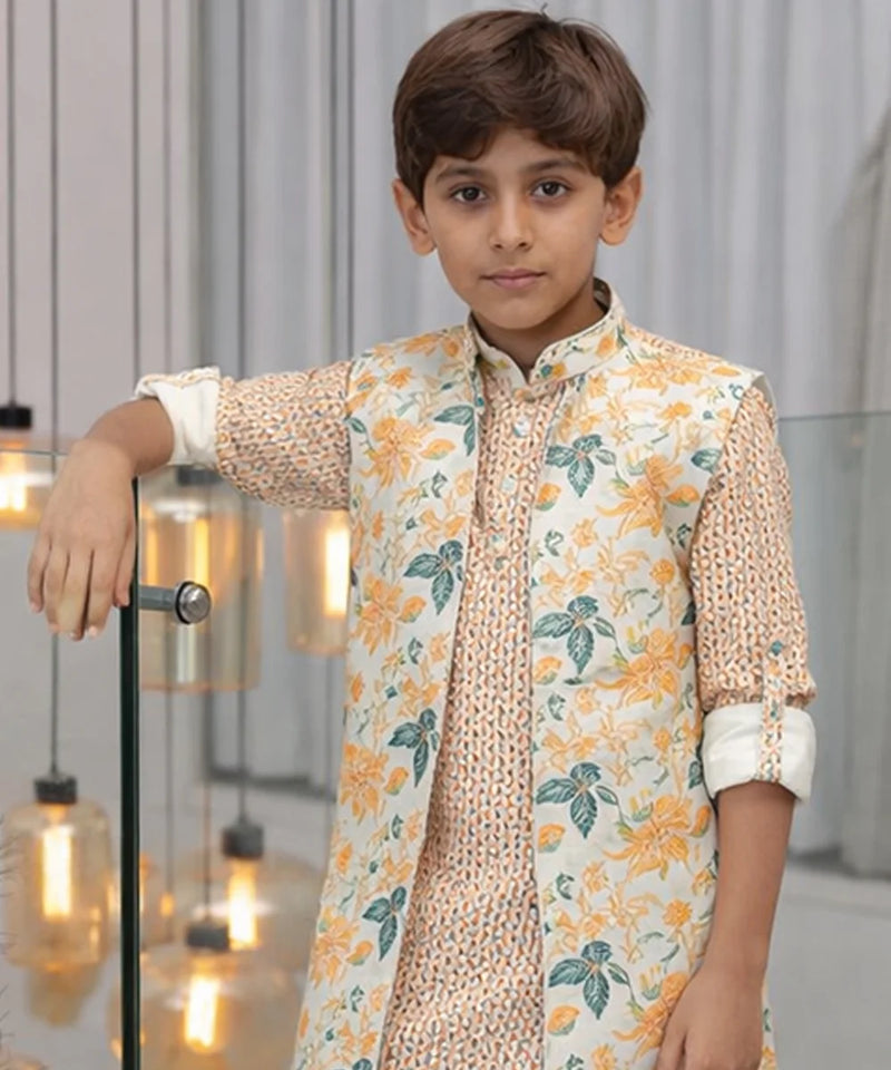 Young boy wearing a floral outfit in an indoor setting with decorative lights.