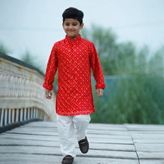 Child wearing a red kurta with white patterns on a wooden bridge