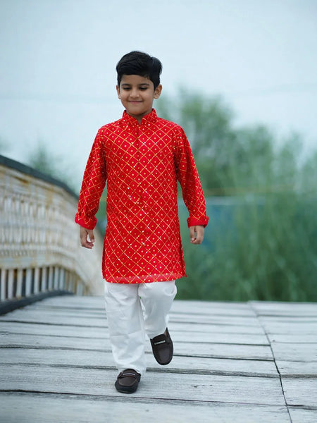Child wearing a red kurta with white patterns on a wooden bridge
