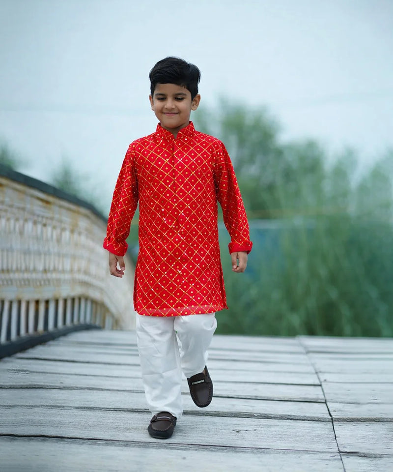 Child wearing a red kurta with white patterns on a wooden bridge
