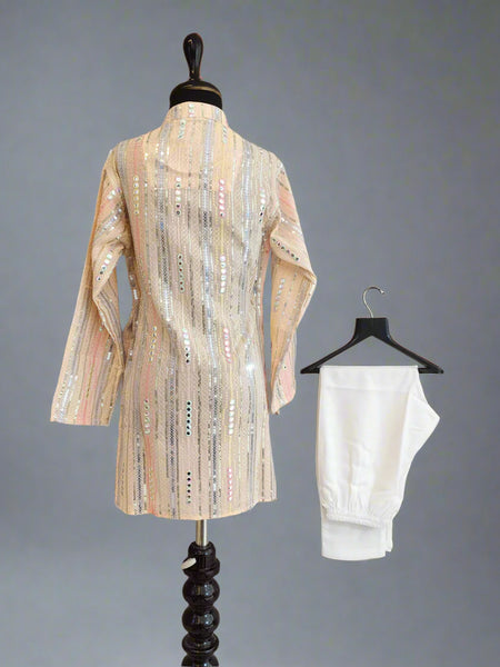 Mannequin wearing a patterned dress with a white garment on a hanger against a gray background
