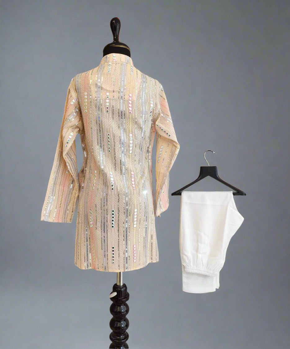 Mannequin wearing a patterned dress with a white garment on a hanger against a gray background
