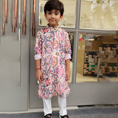 Child wearing a floral kurta standing in front of a store entrance.