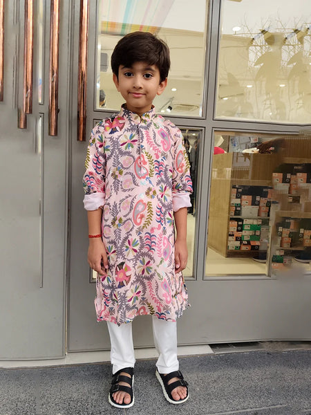 Child wearing a floral kurta standing in front of a store entrance.