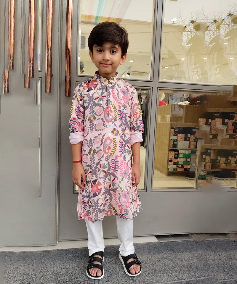 Child wearing a floral kurta standing in front of a store entrance.