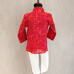 Red patterned kurta with white pants on a mannequin against a beige background