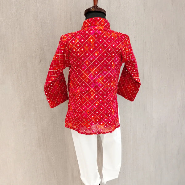 Red patterned kurta with white pants on a mannequin against a beige background