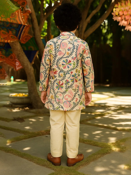Person wearing a floral embroidered jacket and beige pants in an outdoor setting with trees and decorations.