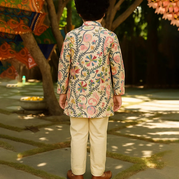 Person wearing a floral embroidered jacket and beige pants in an outdoor setting with trees and decorations.