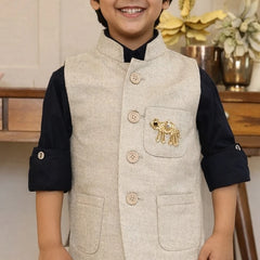 Child wearing a beige vest with an elephant emblem indoors