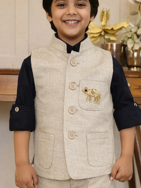 Child wearing a beige vest with an elephant emblem indoors
