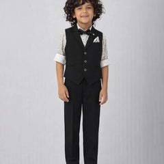 Young boy wearing a formal black vest and pants outfit on a gray background