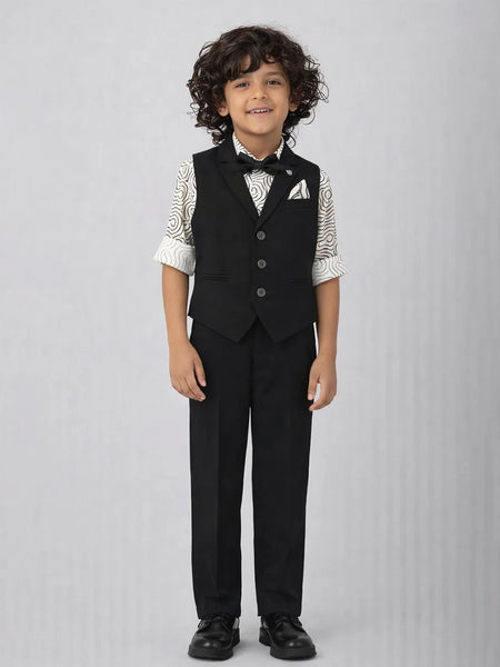 Young boy wearing a formal black vest and pants outfit on a gray background