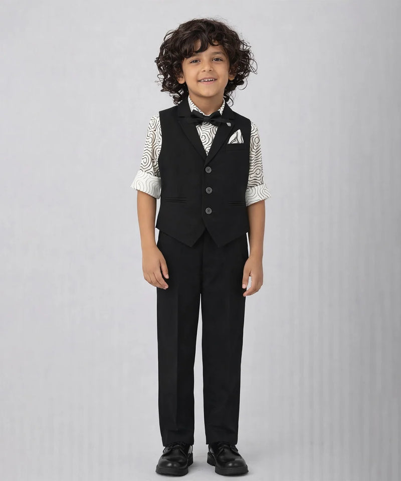 Young boy wearing a formal black vest and pants outfit on a gray background