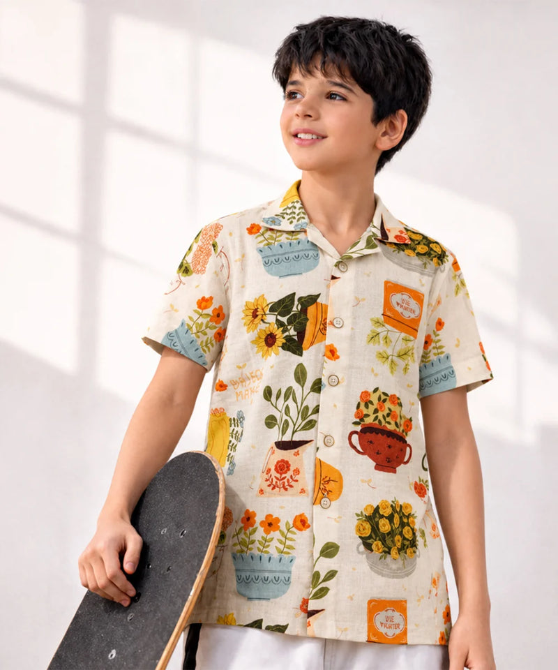 Child wearing a colorful shirt with floral and teacup patterns, holding a skateboard.