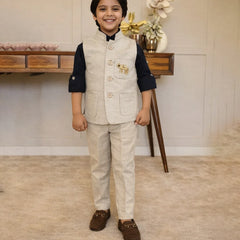 Young boy in formal attire standing in a room with a wooden table and decorative items.