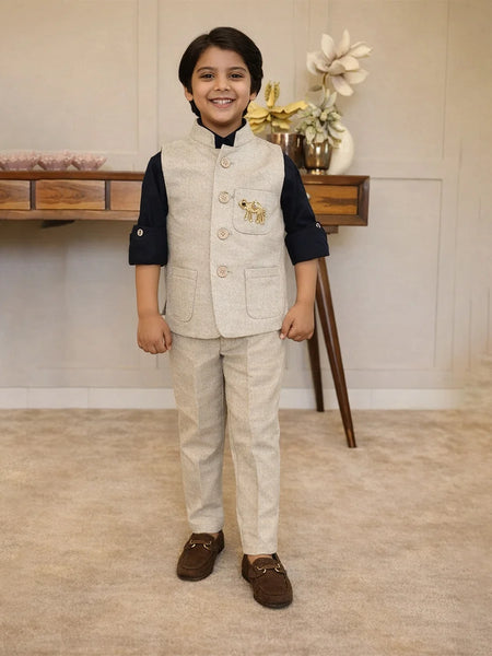 Young boy in formal attire standing in a room with a wooden table and decorative items.