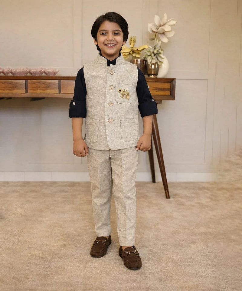 Young boy in formal attire standing in a room with a wooden table and decorative items.