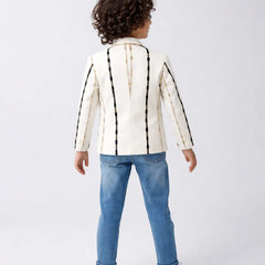 Child wearing a white jacket with black stripes and blue jeans on a white background