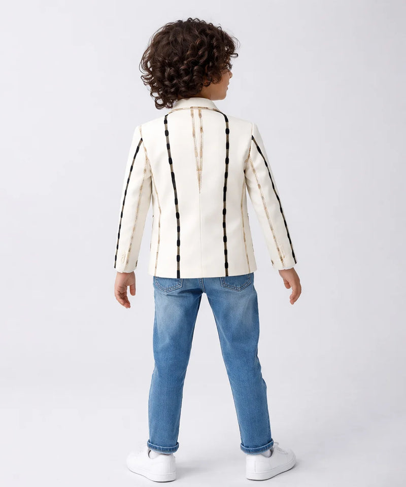 Child wearing a white jacket with black stripes and blue jeans on a white background
