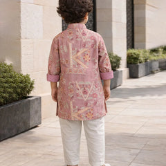Child wearing a pink embroidered kurta with white pants standing outdoors.