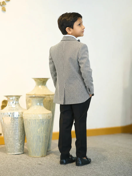 Young boy in a gray suit standing in front of decorative vases.