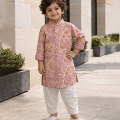 Child wearing a pink floral kurta with white pants standing outdoors.