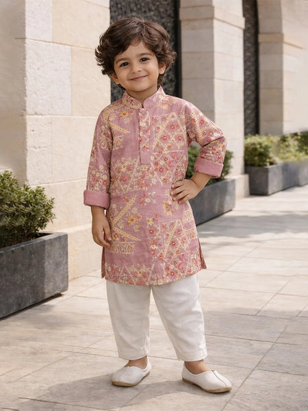 Child wearing a pink floral kurta with white pants standing outdoors.