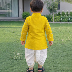 Child wearing a yellow kurta with white dhoti standing on grass