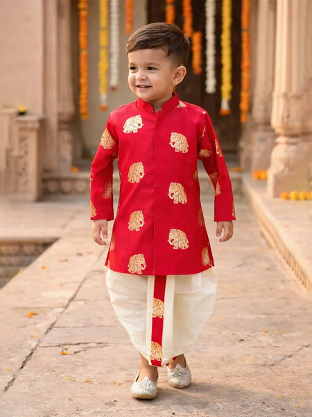 Child wearing a red kurta with gold patterns in an outdoor setting