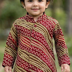 Child wearing a patterned kurta with a blurred natural background