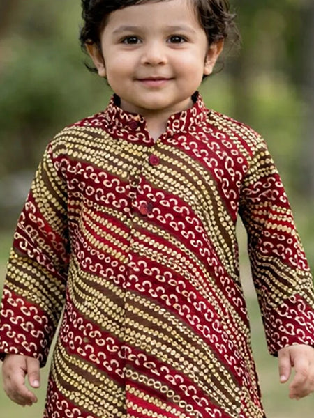 Child wearing a patterned kurta with a blurred natural background