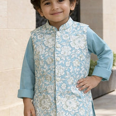Child wearing a light blue floral vest over a matching shirt outdoors.