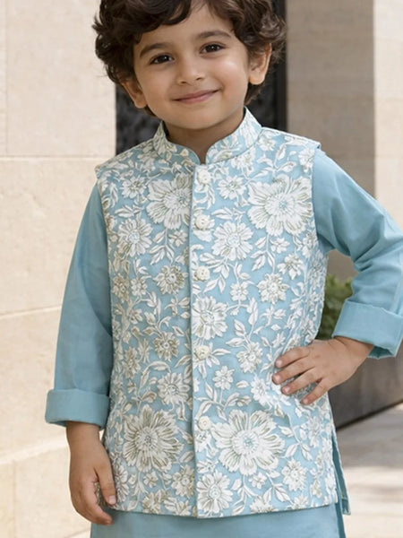 Child wearing a light blue floral vest over a matching shirt outdoors.