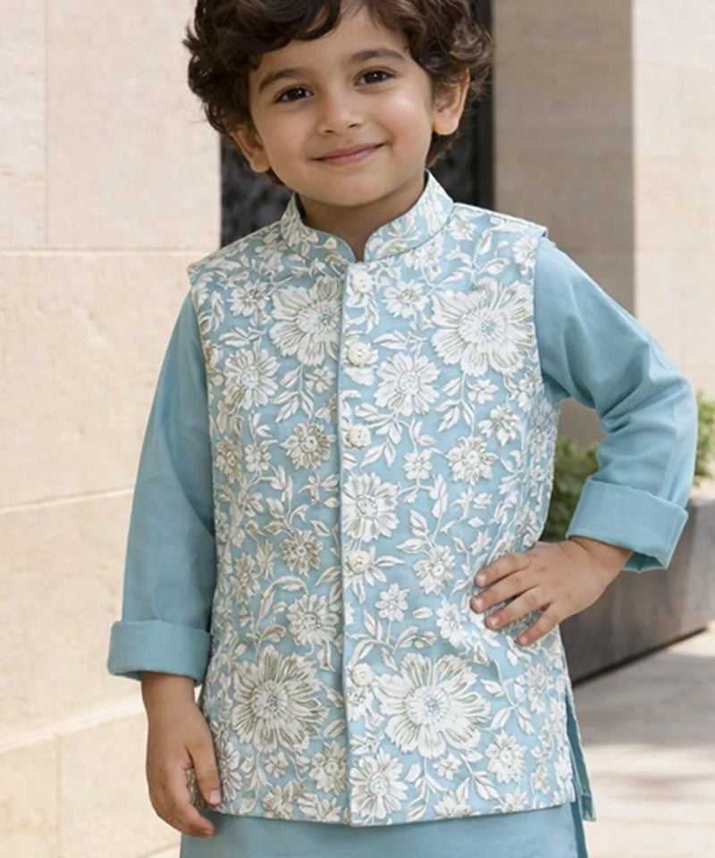 Child wearing a light blue floral vest over a matching shirt outdoors.