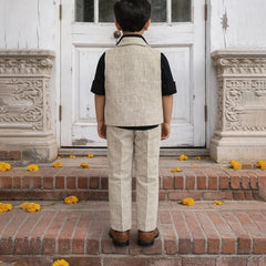 Person wearing a beige vest and pants standing on steps with decorative flowers.
