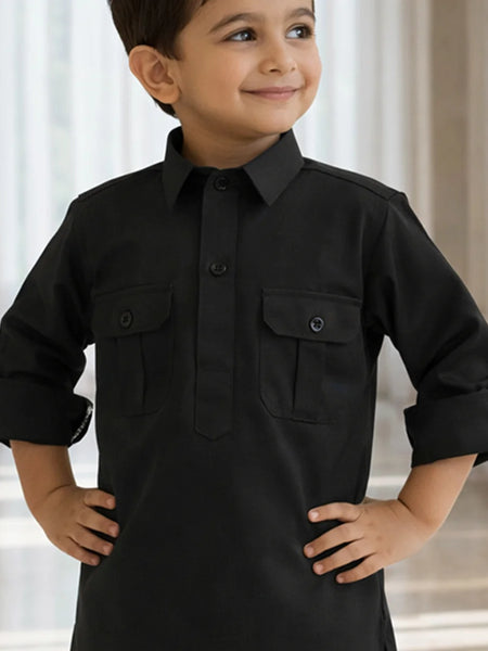 Child wearing a black long-sleeve shirt with pockets against a neutral background