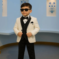 Young boy in a formal suit with sunglasses standing against a light blue wall.